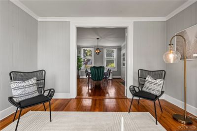 Living area with crown molding, a notable chandelier, wooden walls, and dark hardwood / wood-style floors | Image 3