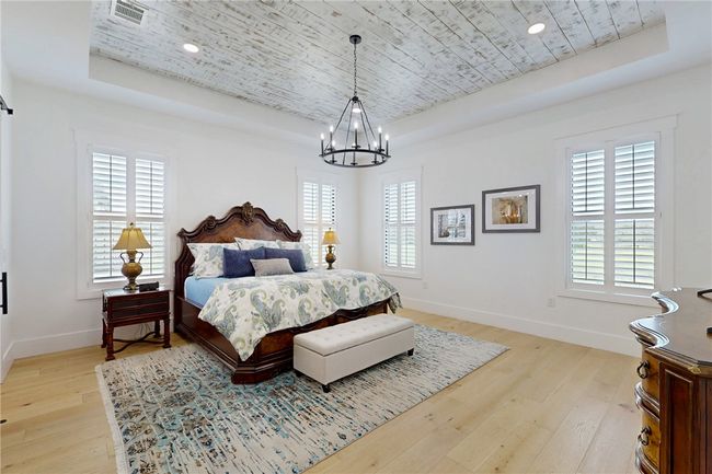 Bedroom featuring a tray ceiling, wooden ceiling, a chandelier, light wood-style floors, and baseboards | Image 16