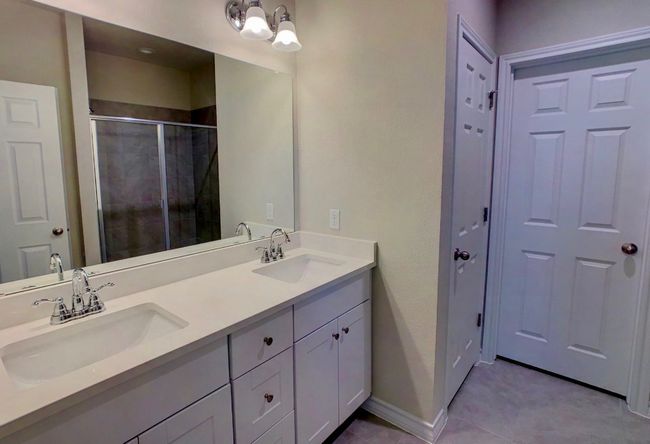 Full bathroom with a shower stall, double vanity, baseboards, and a sink | Image 12