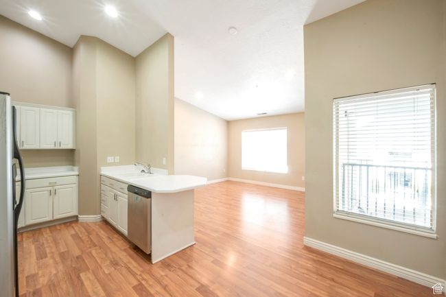 Kitchen with a peninsula, appliances with stainless steel finishes, light wood-style floors, light countertops, and white cabinetry | Image 5