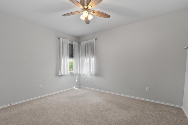 This bedroom includes a high ceiling, a ceiling fan, and a walk-in closet. | Image 24