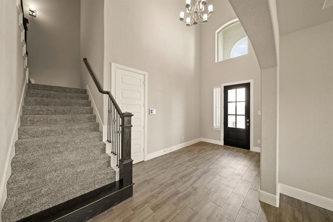 Soaring ceilings, elegant chandelier, and wood-look tile flooring create a warm and sophisticated welcome. | Image 5
