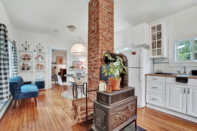 Kitchen with white cabinets, freestanding refrigerator, light wood-style flooring, and glass insert cabinets | Image 4