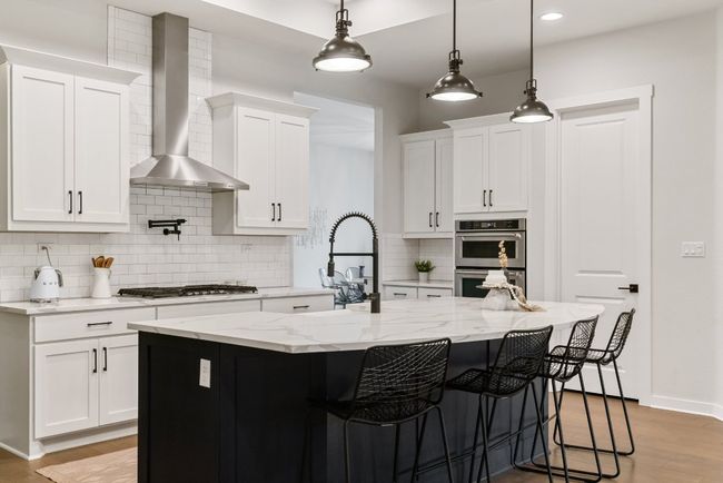Kitchen with wall chimney range hood, stainless steel appliances, decorative backsplash, light wood-type flooring, and white cabinets | Image 10