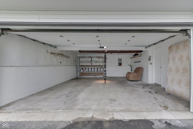 garage featuring concrete block wall, electric panel, and a garage door opener | Image 25