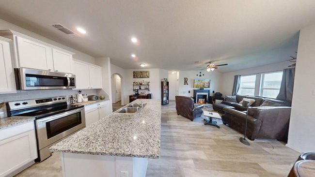 Kitchen with stainless steel appliances, arched walkways, a center island with sink, a sink, and white cabinets | Image 19
