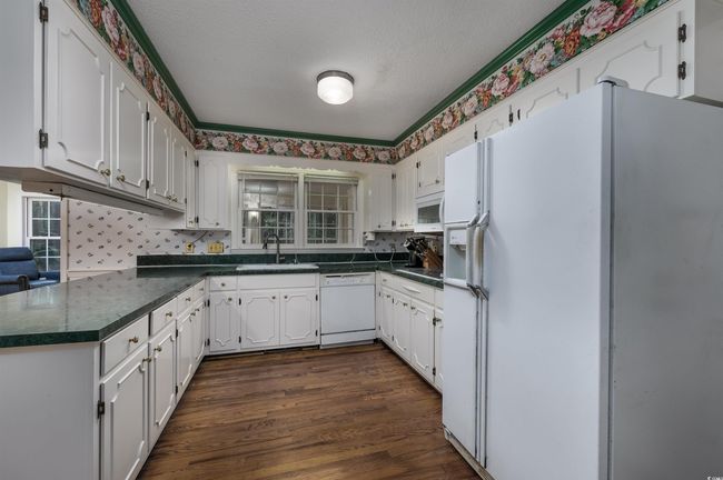 Kitchen featuring white appliances, a textured ceiling, white cabinetry, sink, and dark wood-type flooring | Image 15
