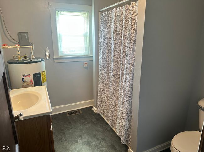 bathroom featuring toilet, electric water heater, baseboards, visible vents, and vanity | Image 9