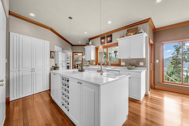 Kitchen with ornamental molding, a center island with sink, plenty of natural light, white cabinets, and light wood-style floors | Image 18