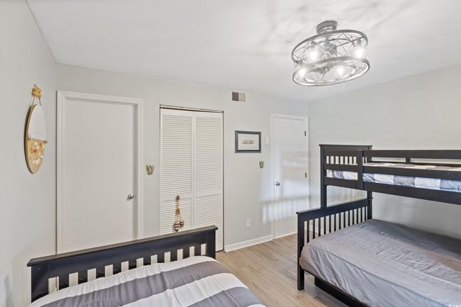 Bedroom featuring visible vents, baseboards, a closet, light wood finished floors, and a chandelier | Image 20