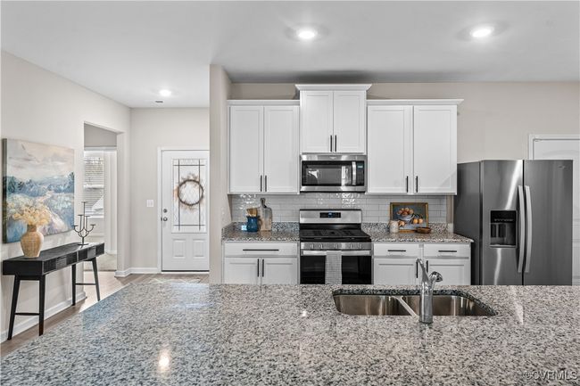 Kitchen with stainless steel appliances, a sink, white cabinets, tasteful backsplash, and light stone countertops | Image 17