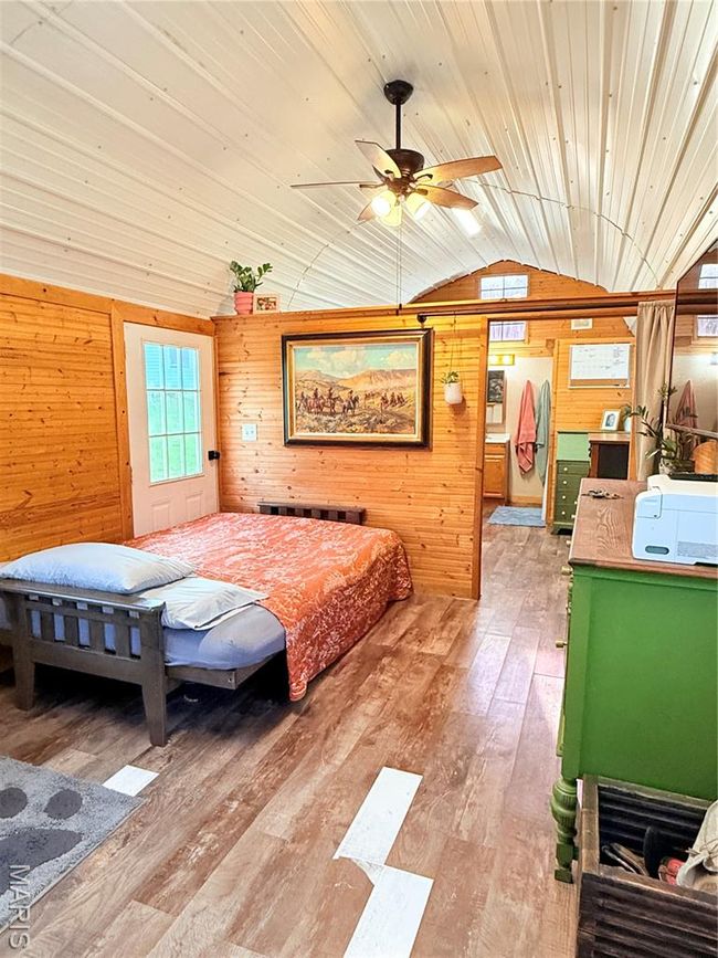 Bedroom with vaulted ceiling, wooden walls, hardwood / wood-style floors, and wood ceiling | Image 12