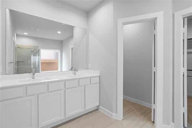 This primary bathroom is definitely move-in ready! Featuring dual vanities, stained wood cabinets with light countertops, spacious walk-in closet with shelving, high ceilings, custom paint, sleek and modern finishes. | Image 11