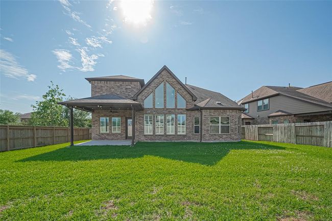 Backyard of a brick home with a large patio and expansive windows, perfect for natural light. The yard is surrounded by a wooden fence, offering privacy in a serene suburban setting. | Image 41