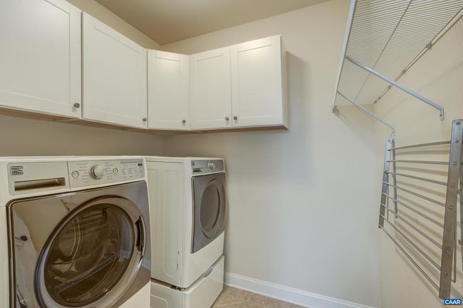 Main level laundry room with pedestal washer and dryer, storage cabinets and drying rack. | Image 25