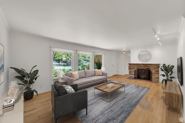 Living area featuring track lighting, wood finished floors, a fireplace, ornamental molding, and baseboards | Image 11