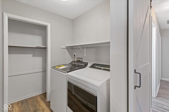 laundry area featuring washer and dryer, light wood-type flooring, and a textured ceiling | Image 16