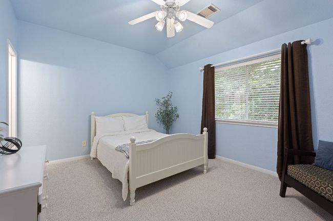 Bedroom with light colored carpet, vaulted ceiling, baseboards, and a ceiling fan | Image 20