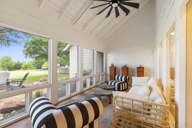 Sunroom featuring a ceiling fan, high vaulted ceiling, an outdoor living space, a wooden ceiling with exposed beams, and wood walls | Image 27