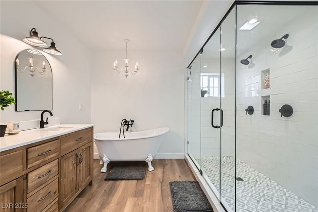 Bathroom featuring vanity, a freestanding tub, a chandelier, a shower stall, and wood finished floors | Image 21