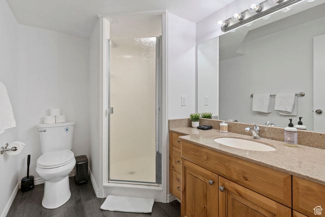 Bathroom featuring vanity, hardwood / wood-style floors, a shower with door, and toilet | Image 25