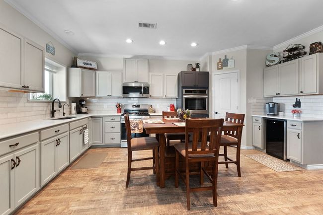 Kitchen featuring beverage cooler, visible vents, a sink, appliances with stainless steel finishes, and light wood-type flooring | Image 7