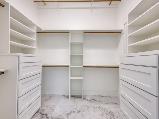 Spacious custom closet featuring light marble finish floors, build in shelves and drawers | Image 35
