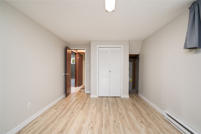 Unfurnished bedroom with a baseboard radiator, light wood finished floors, a closet, water heater, and baseboards | Image 24