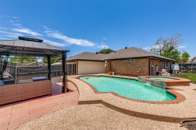 View of pool featuring a gazebo, a patio, a fenced backyard, and a pool with connected hot tub | Image 23