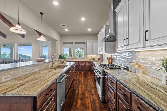 Kitchen with wall chimney exhaust hood, stainless steel appliances, white cabinets, dark wood-style floors, and a sink | Image 15
