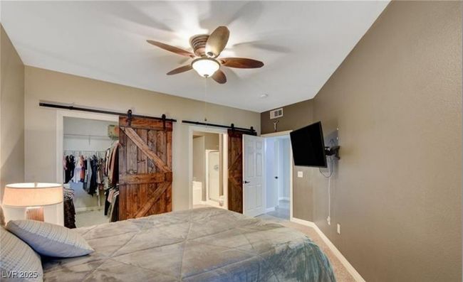 Carpeted bedroom featuring a barn door, a closet, visible vents, baseboards, and a spacious closet | Image 12