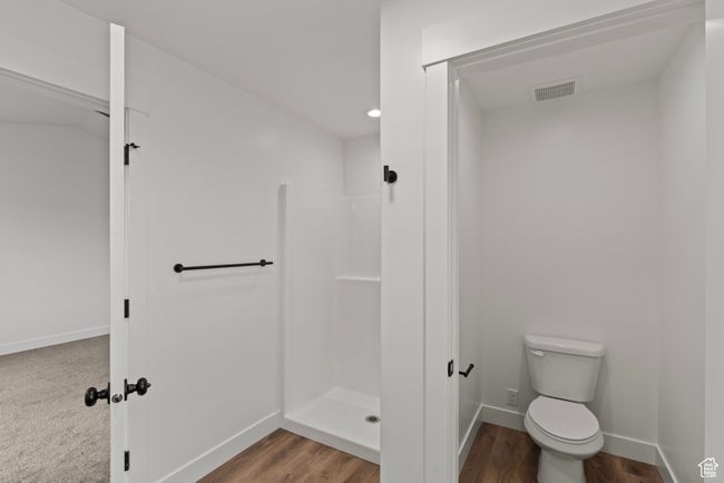 Bathroom featuring walk in shower, toilet, baseboards, and wood finished floors | Image 13