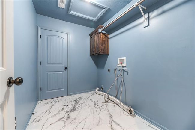 Laundry area featuring cabinet space, electric dryer hookup, attic access, marble finish flooring, and washer hookup | Image 31
