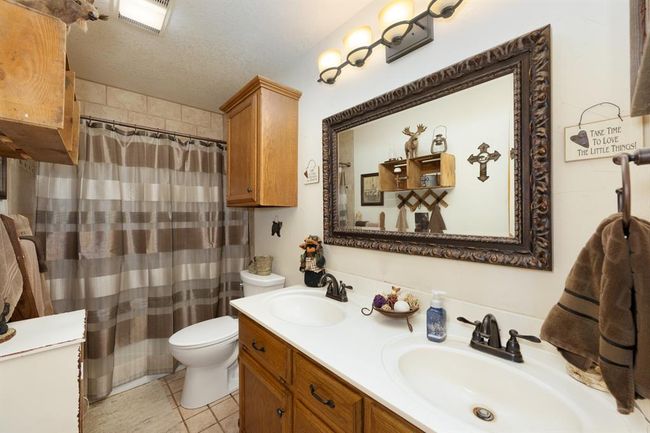Full bathroom with double vanity, toilet, a sink, and a textured ceiling | Image 25