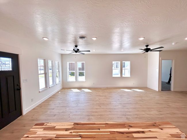 Unfurnished living room with ceiling fan and a wealth of natural light | Image 7