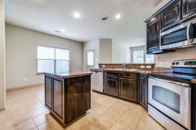 Kitchen featuring appliances with stainless steel finishes, recessed lighting, a center island, light tile patterned floors, and a peninsula | Image 9