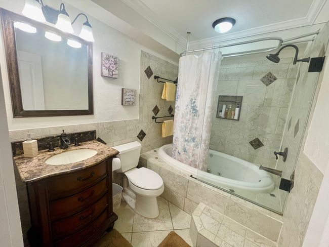 Bathroom featuring tiled shower / bath, tile walls, crown molding, toilet, and vanity | Image 19