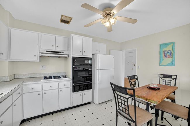Kitchen featuring white appliances, a warming drawer, under cabinet range hood, a ceiling fan, and light countertops | Image 21