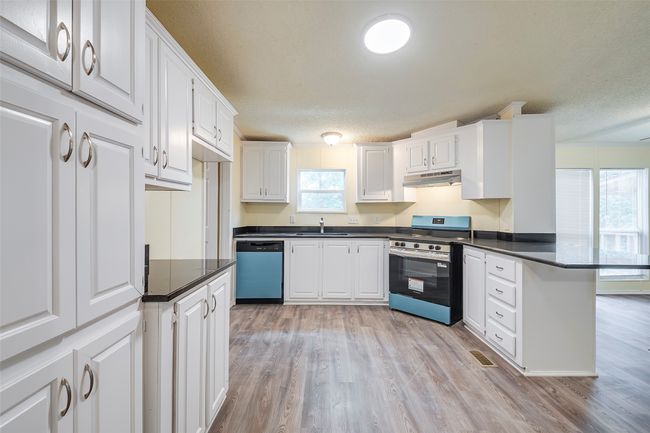 Kitchen featuring stainless steel range oven, dishwasher, under cabinet range hood, a peninsula, and a sink | Image 4