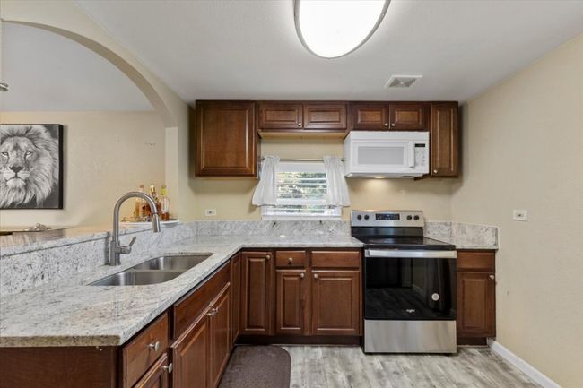 Kitchen featuring white microwave, light wood-style flooring, a peninsula, a sink, and stainless steel electric range | Image 8