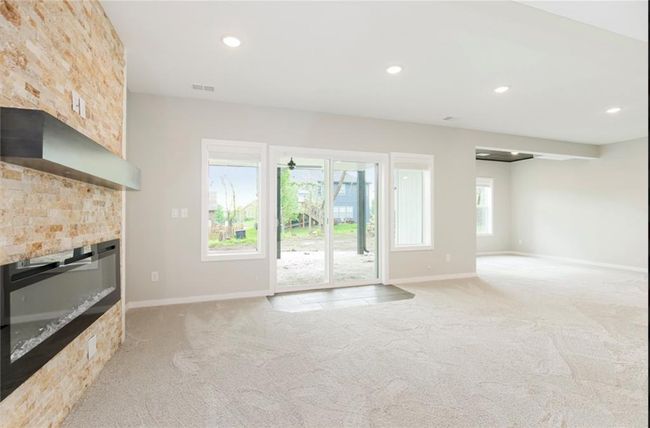 Unfurnished living room with light carpet, a large fireplace, baseboards, and recessed lighting | Image 15