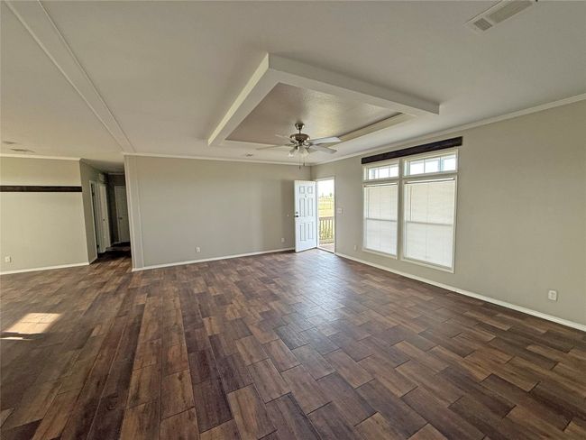 Spare room featuring dark wood-style floors, a tray ceiling, and ceiling fan | Image 8
