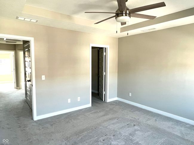 Primary bedroom with tray ceiling, custom blinds, ceiling fan & customized walk-in closet | Image 44