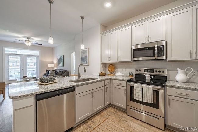 Kitchen featuring a sink, open floor plan, light wood-type flooring, a peninsula, and stainless steel appliances | Image 27