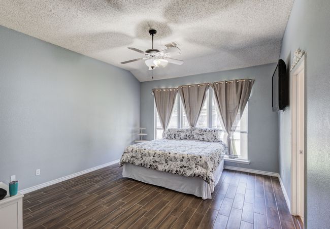 Bedroom featuring baseboards, dark wood-style floors, a textured ceiling, and ceiling fan | Image 8