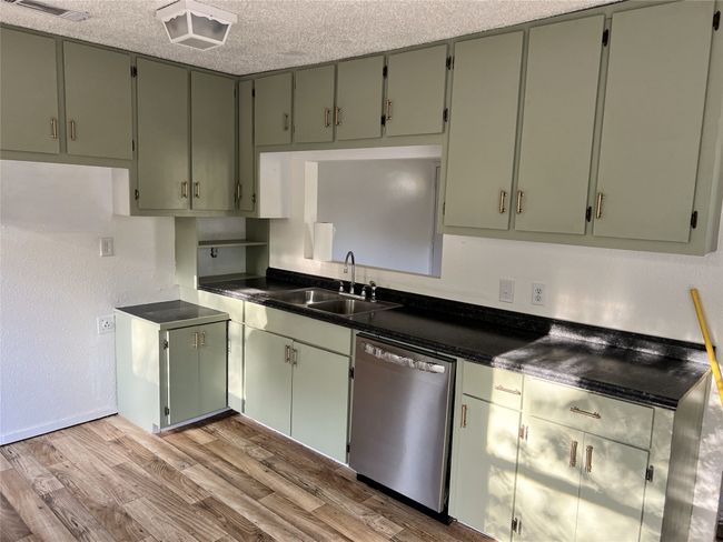 Kitchen with a sink, stainless steel dishwasher, dark countertops, and light wood-style flooring | Image 5