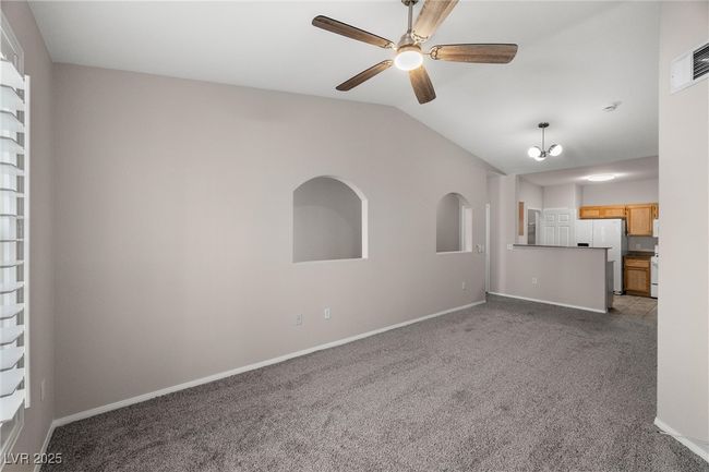 Unfurnished living room featuring ceiling fan, visible vents, baseboards, light colored carpet, and lofted ceiling | Image 13