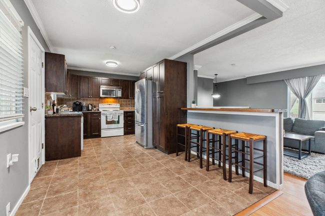 Kitchen with stainless steel appliances, tasteful backsplash, crown molding, and dark brown cabinets | Image 11