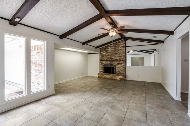 Unfurnished living room with a textured ceiling, light tile patterned flooring, ceiling fan, and a​​‌​​​​‌​​‌‌​‌‌​​​‌‌​​‌‌​‌​​​​​‌ fireplace | Image 4