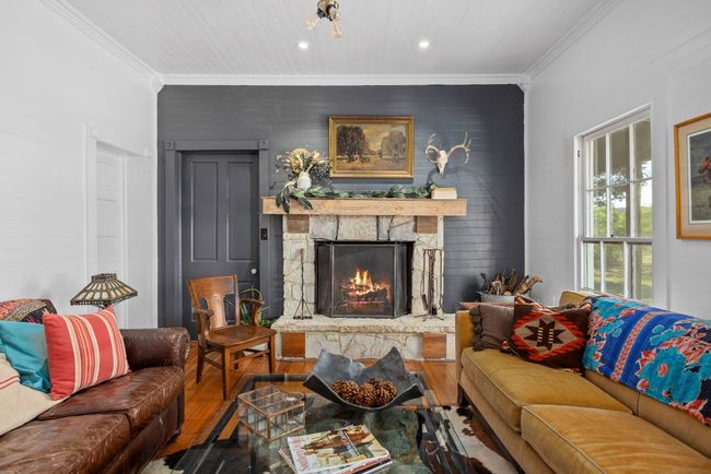 Living area featuring hardwood / wood-style flooring, ornamental molding, an accent wall, a stone fireplace, and recessed lighting | Image 6